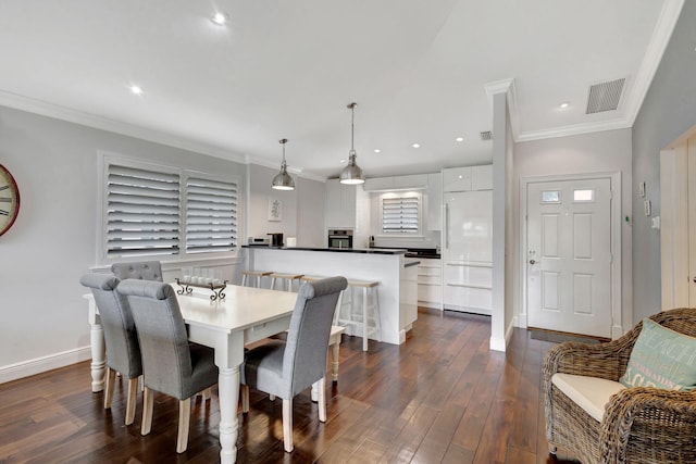 dining room with ornamental molding and dark hardwood / wood-style flooring