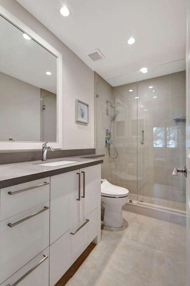 bathroom featuring a shower with door, vanity, tile patterned floors, and toilet