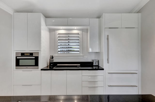 kitchen with black electric cooktop, oven, and white cabinets