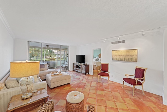 living room with ornamental molding, rail lighting, light tile patterned floors, and a textured ceiling