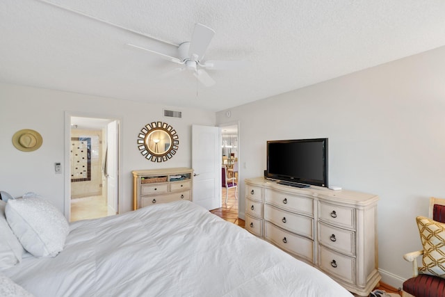 bedroom with ceiling fan, a textured ceiling, and ensuite bath