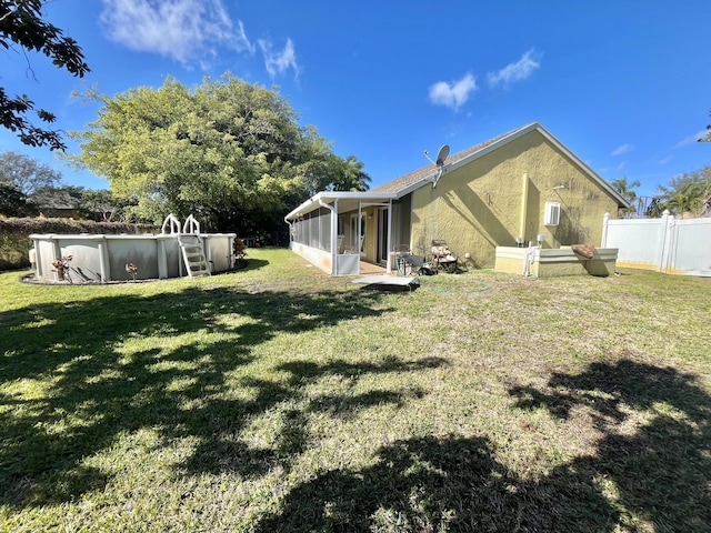 rear view of house featuring a sunroom and a lawn