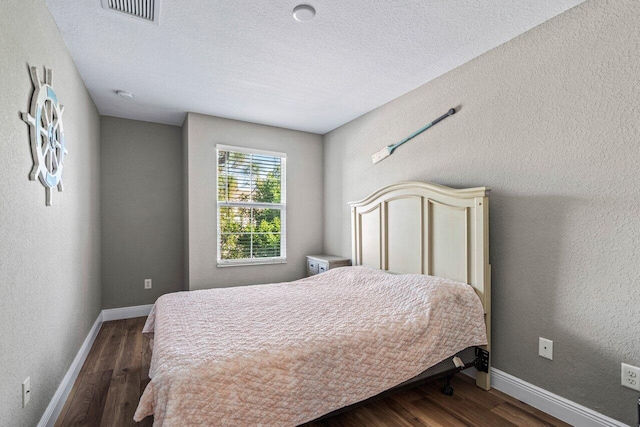 bedroom featuring dark wood-type flooring and a textured ceiling