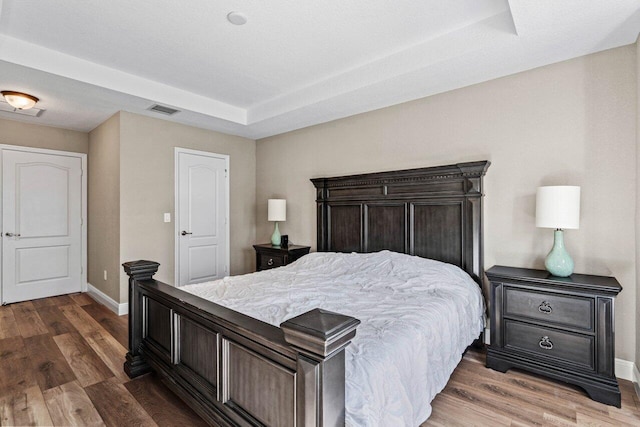 bedroom featuring hardwood / wood-style flooring and a raised ceiling