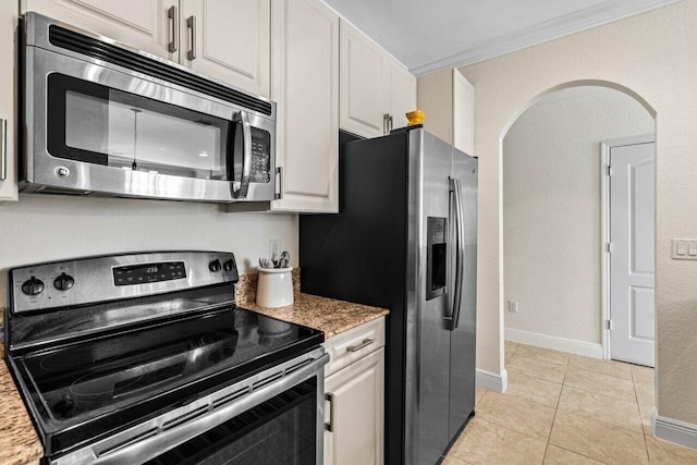 kitchen featuring light tile patterned flooring, appliances with stainless steel finishes, white cabinets, crown molding, and light stone countertops