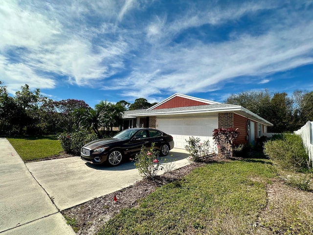 view of side of property featuring brick siding, a yard, an attached garage, fence, and driveway