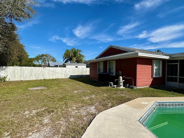 rear view of house featuring a fenced in pool and a lawn