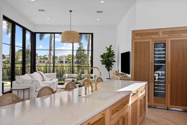 2578 Players Ct, Wellington, FL 33414 - kitchen featuring hanging light fixtures, light stone countertops, sink, and light wood-type flooring