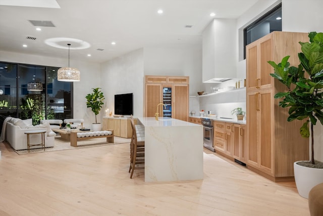 2578 Players Ct, Wellington, FL 33414 - kitchen featuring sink, hanging light fixtures, a kitchen island with sink, wall oven, and light hardwood / wood-style flooring