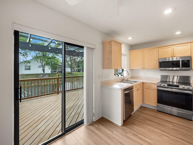 kitchen featuring stainless steel appliances, sink, light hardwood / wood-style flooring, and light brown cabinets