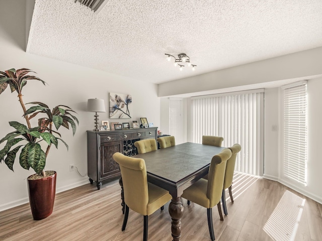 dining room with a textured ceiling and light hardwood / wood-style floors