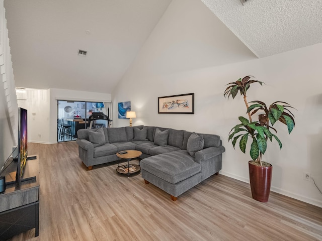 living room with high vaulted ceiling and light wood-type flooring