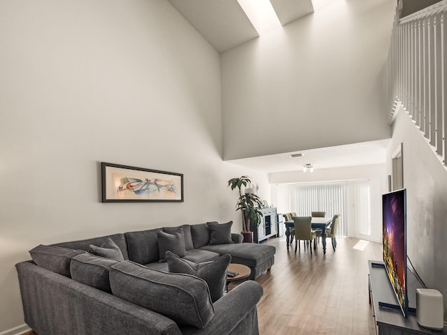 living room with light hardwood / wood-style floors and a high ceiling