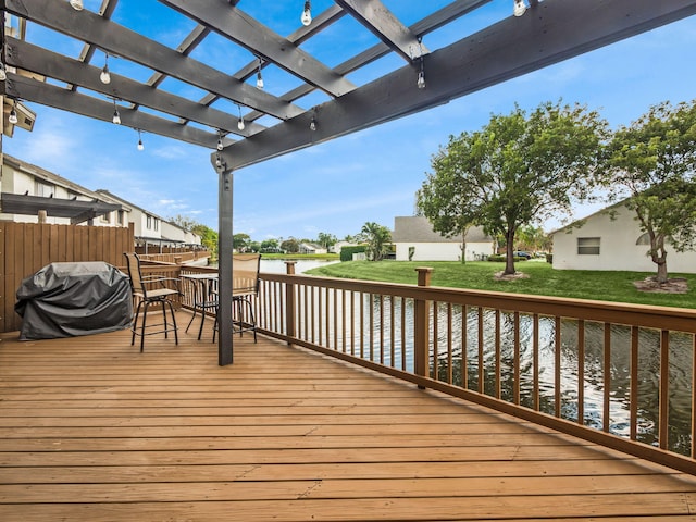 wooden deck with a water view, a lawn, grilling area, and a pergola