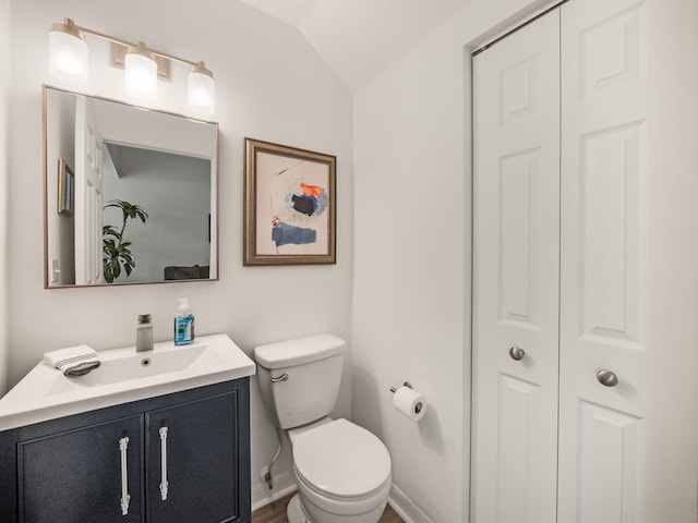 bathroom featuring vanity, vaulted ceiling, and toilet