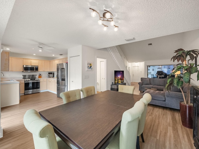 dining room with sink, light hardwood / wood-style flooring, a textured ceiling, and ceiling fan