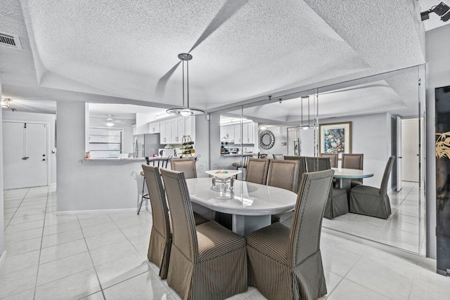 dining room with a raised ceiling, ceiling fan, light tile patterned floors, and a textured ceiling