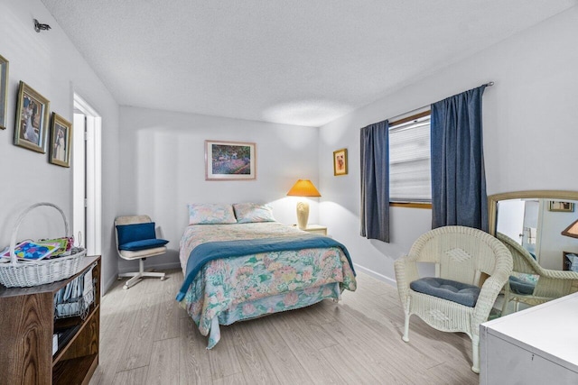 bedroom with a textured ceiling and light wood-type flooring