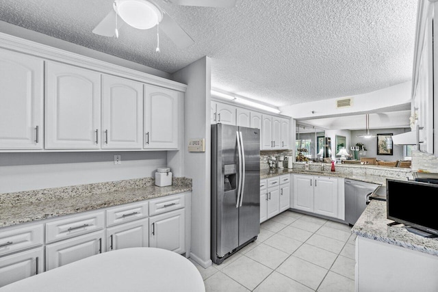 kitchen with stainless steel appliances, light tile patterned floors, white cabinets, and kitchen peninsula