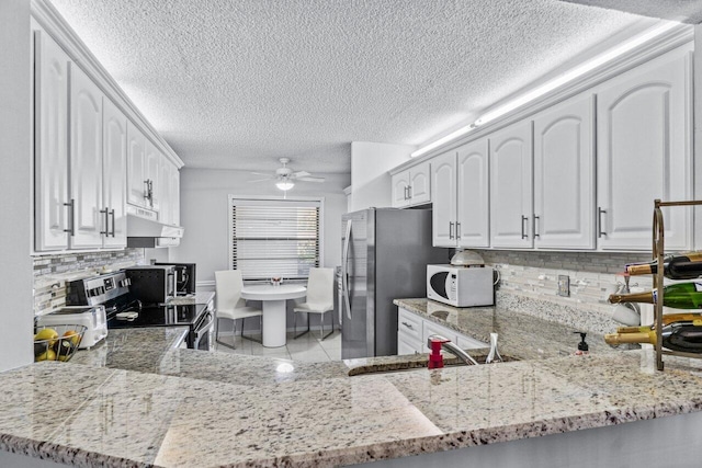 kitchen featuring kitchen peninsula, white cabinets, ceiling fan, stainless steel appliances, and backsplash