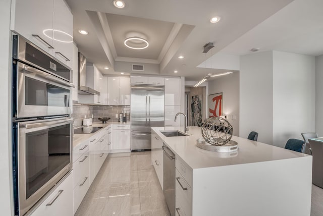 kitchen with white cabinetry, hanging light fixtures, a tray ceiling, a kitchen breakfast bar, and stainless steel appliances