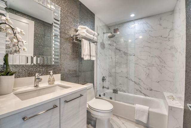 full bathroom with tiled shower / bath, tile walls, vanity, and toilet