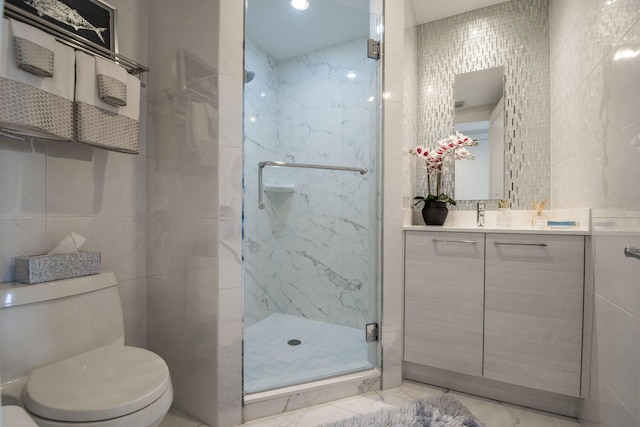 bathroom featuring vanity, toilet, a shower with door, and tile walls