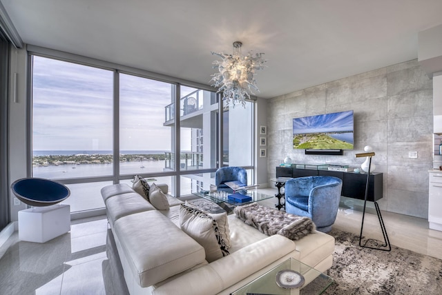 living room featuring a notable chandelier, a wall of windows, and a water view