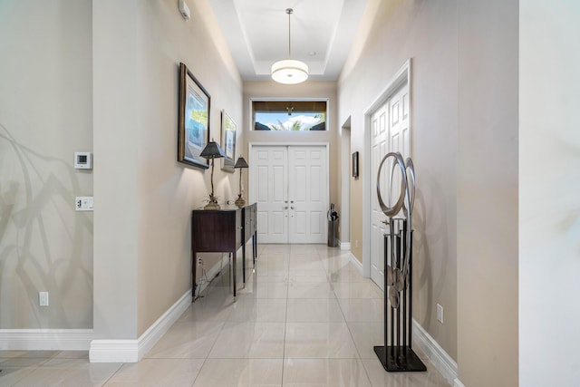 foyer with a raised ceiling and light tile patterned floors