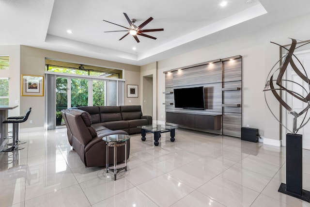 living room with a tray ceiling and ceiling fan