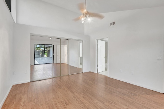 unfurnished bedroom featuring light wood-type flooring, baseboards, visible vents, and high vaulted ceiling