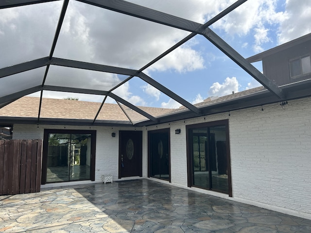 back of property featuring glass enclosure, a patio area, and brick siding