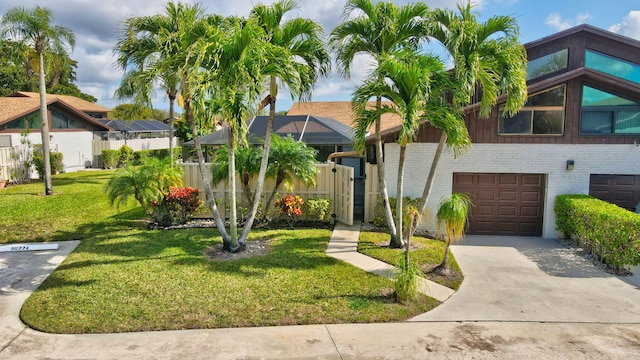 view of front of property with an attached garage, a lanai, brick siding, concrete driveway, and a front yard