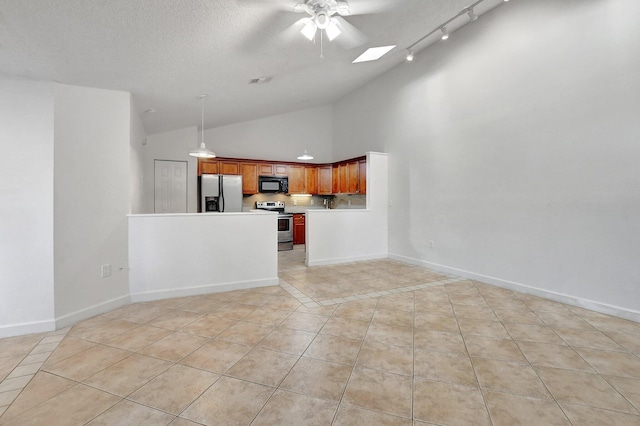 interior space featuring a ceiling fan, lofted ceiling with skylight, baseboards, and light tile patterned floors