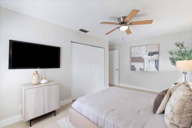 bedroom with light hardwood / wood-style floors, ceiling fan, and a closet