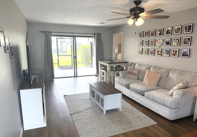 living room with ceiling fan, dark hardwood / wood-style floors, and a textured ceiling