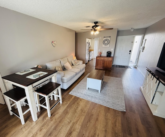 living room featuring a textured ceiling, hardwood / wood-style floors, and ceiling fan