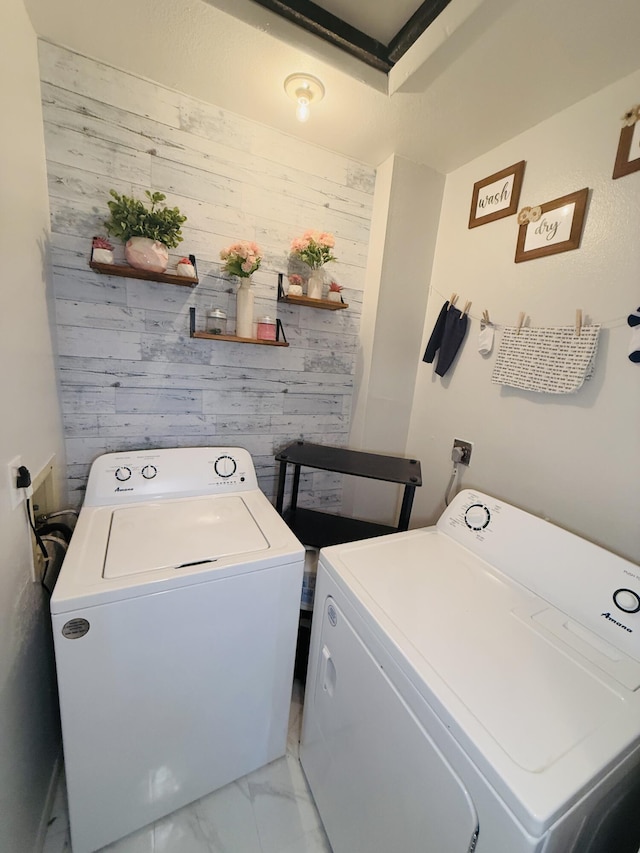 clothes washing area featuring independent washer and dryer and wood walls