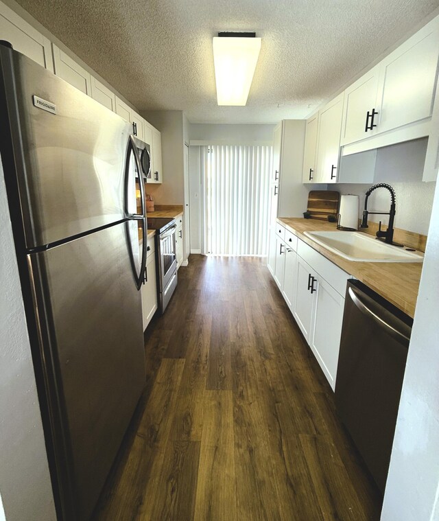 kitchen with butcher block countertops, sink, stainless steel appliances, and white cabinets