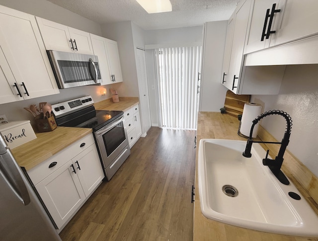 kitchen with sink, white cabinetry, a textured ceiling, stainless steel appliances, and dark wood-type flooring