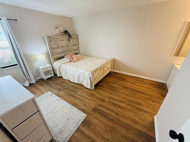 bedroom with a textured ceiling and dark hardwood / wood-style flooring