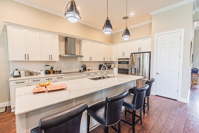 kitchen with wall chimney exhaust hood, sink, a center island with sink, and white cabinets