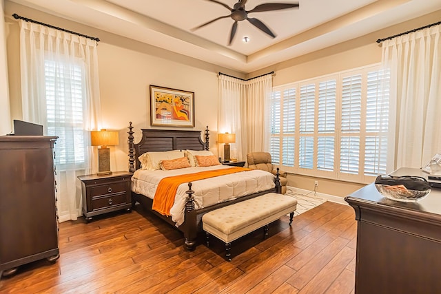 bedroom featuring hardwood / wood-style floors, ceiling fan, and a tray ceiling