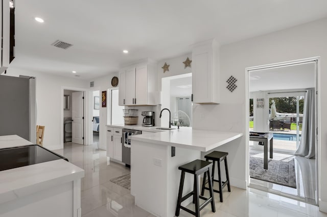 4448 SW 34th Ter, Dania Beach, FL 33312 - kitchen featuring freestanding refrigerator, a sink, white cabinets, a kitchen breakfast bar, and recessed lighting