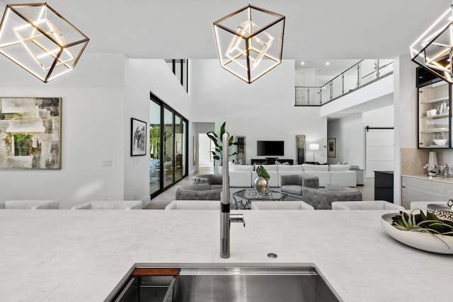 kitchen featuring a barn door, a towering ceiling, an inviting chandelier, and decorative light fixtures