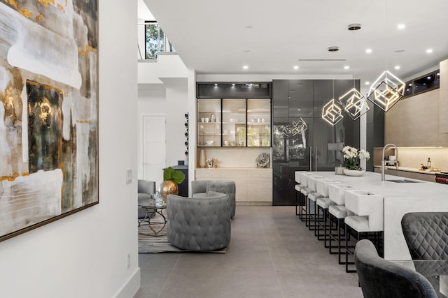 interior space featuring a towering ceiling, decorative light fixtures, gray cabinets, and sink