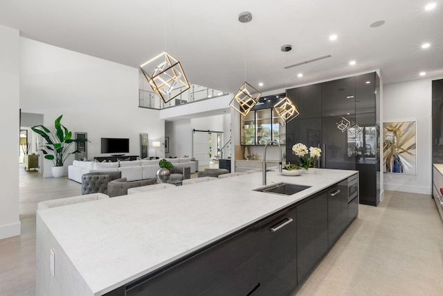 kitchen featuring a large island, sink, pendant lighting, a towering ceiling, and a barn door