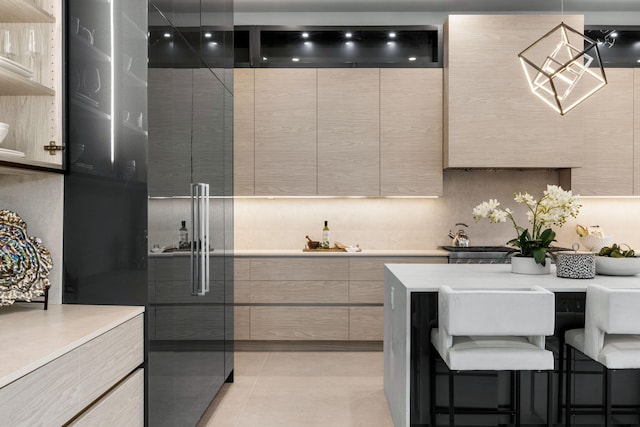 kitchen with light brown cabinetry, hanging light fixtures, a breakfast bar, and light tile patterned flooring