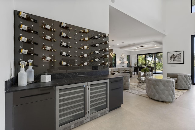 bar with wine cooler, fridge, and dark stone countertops