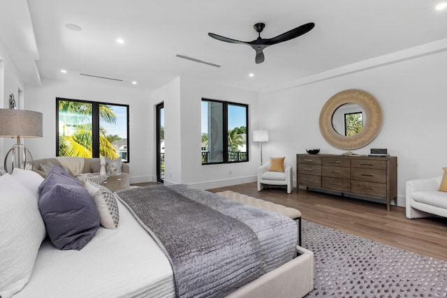 bedroom featuring multiple windows, hardwood / wood-style flooring, and ceiling fan